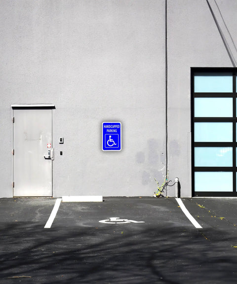 Heavy Duty Aluminum Handicap Parking Sign Ada Compliant Reflective Metal Plaque next to a parking spot on a wall.