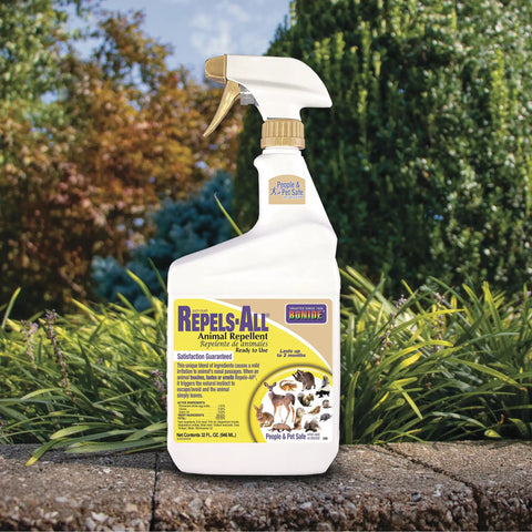 Repels All Animal Repellent Ready To Use Spray 32 Oz bottle in garden setting with green shrubbery background