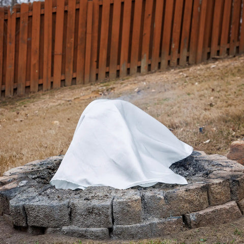 Emergency Fire Blanket 40 By 40 Inches covering a fire pit, made of woven fiberglass, ideal for smothering small fires safely outdoors.