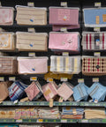 Retail display of colorful towels and fabric storage bags on shelves with various patterns and designs.