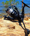 Loaded Spinning Reel With 10lb Braided Line, Carbon Disc Drag, 5.2 To 1 Gear, 7 Plus 1 Bearings on a log by water