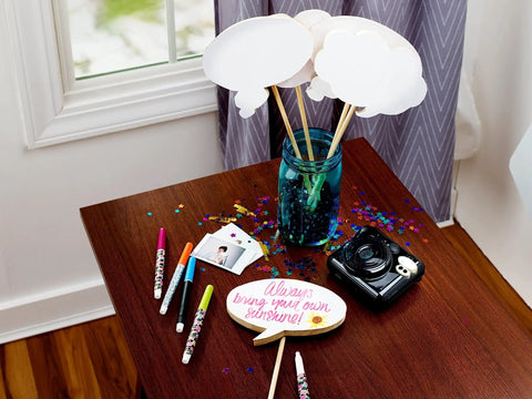 Crafting table with supplies including markers and camera, possibly using White Dry Erase Tape 1.88 Inch Wide By 5 Yard Length 6 Pack