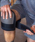 A person wearing extra thick waterproof neoprene work knee pads for men and women, adjusting strap for kneeling protection.
