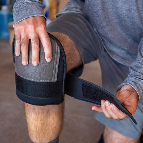 A person wearing extra thick waterproof neoprene work knee pads for men and women, adjusting strap for kneeling protection.