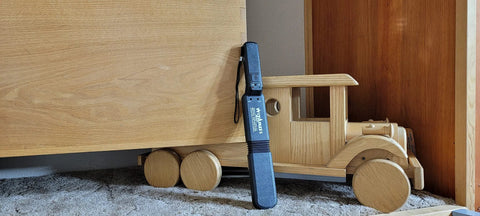 Lumber Wizard 5 metal detector for woodworking, blue handheld unit leaning against a wooden wheeled cart.