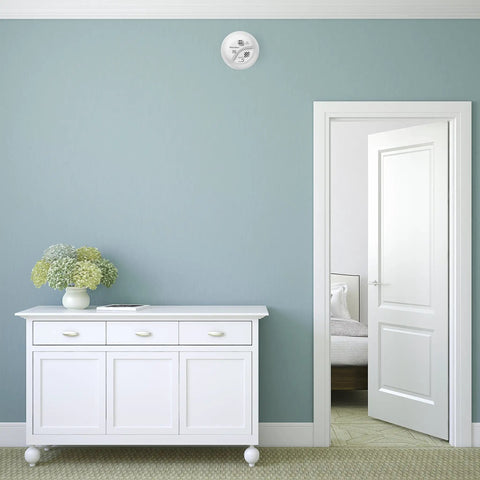 Hardwired Heat Alarm With Battery Backup For Home Safety Rate Of Rise Sensing Microprocessor Controlled To Cut False Alarms Remotely Test And Mute Ideal For Kitchens Garages Attics And Areas Where Smoke Detectors Dont Fit installed on a wall above a white cabinet in a blue-walled room.