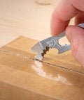 Hand using DoohicKey Keychain Multi Tool Stainless Steel 8 In 1 with serrated edge to open a cardboard box