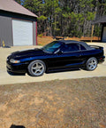 Top Shelf Tinted Blue Paint Basecoat Gallon Ready To Spray With Slow Reducer Blend For Ultra Smooth Automotive Finish That Hits Perfect And Looks Totally Fresh On Any Ride outside a black sports car.