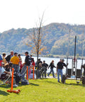 People gathered outdoors with Safety Orange Plastic Barrier Chain, 2-Inch Link, 100-Foot Length for Crowd Control visible at park.