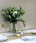 Gold Sequin Wallpaper Roll With Sparkle Finish accenting a dining area with white tableware and floral centerpiece.