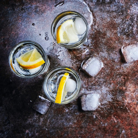 Kick Back Wooden Shooting Board Set With Eighteen Shot Glasses For Chill Game Nights with lemon slices and ice cubes