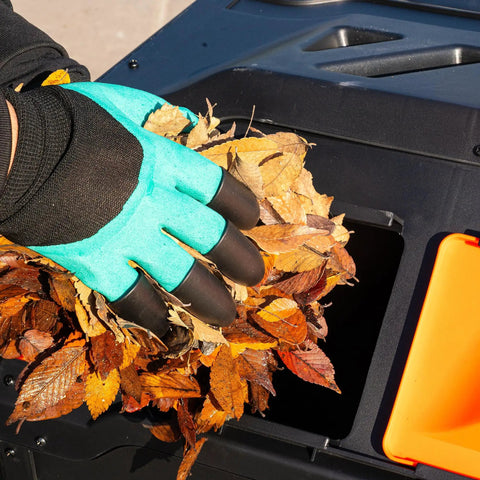 Hand adding leaves to 43 Gallon Dual Chamber Tumbling Compost Bin With Sliding Doors, Rotating Batch Composter For Garden And Kitchen Scraps
