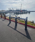 View of waterfront with metal structures on paved surface near water with cranes in the background