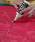 Applying Seam Grip FC Fast Cure Sealant For Tents Rainflies Tarps And Awnings Water Based Seam Sealer on red nylon fabric