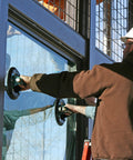 Front view of worker in hard hat using Woods Powr-Grip N6450 10-inch concave vacuum cup with metal handle on glass