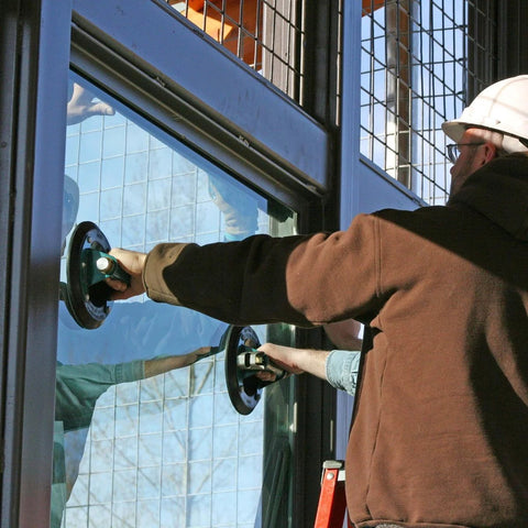 Worker using 8 Inch Flat Vacuum Suction Cup With Metal Handle And Hand Pump on glass window for installation