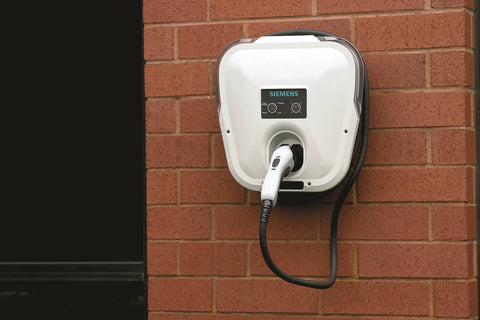Badass Level 2 EV Charger Hard Wired With 30 Amp 240 Volt J1772 Compatibility mounted on brick wall with a charging cable.
