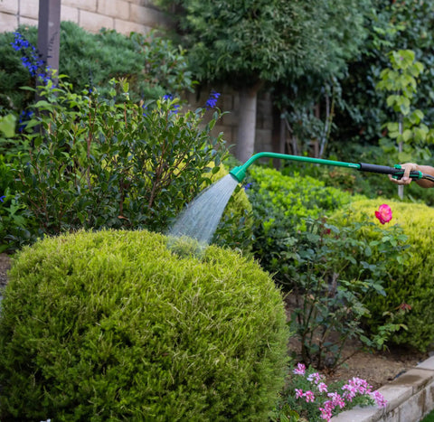 Gardener using 36 Inch Front Trigger Watering Wand Hose Nozzle With Carbon Fiber Texture And Non Slip Grip on bush