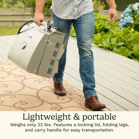 Person carrying Chef's Style Tabletop Portable Propane Grill With 20,000 BTU Stainless Steel Two-Burner Outdoor Gas Grill