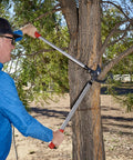 Man using Super Duty 32 Inch Bypass Lopper With MAXFORGED Steel For Heavy Duty Pruning on thick tree branch outdoors.