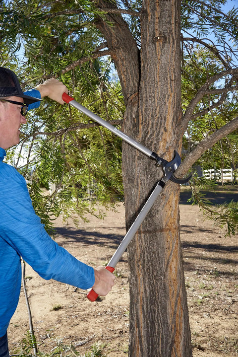 Man using Super Duty 32 Inch Bypass Lopper With MAXFORGED Steel For Heavy Duty Pruning on thick tree branch outdoors.