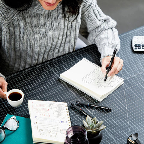Person writing in a notebook with Goes On Like Butter Gel Pens Black 0.7 Mm Medium Point 12 Pack Featuring Zero Smear Quick Dry Ink.