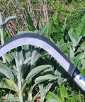Person using K310 Brush Clearing Sickle with 9 Inch SK5 Japanese High Carbon Steel Blade and 9 Inch Aluminum Handle in garden