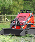 Compact Stand On Crawler Mini Skid Steer Loader With Trencher And 23 HP Gas Engine And Bucket Attachment in a grassy area
