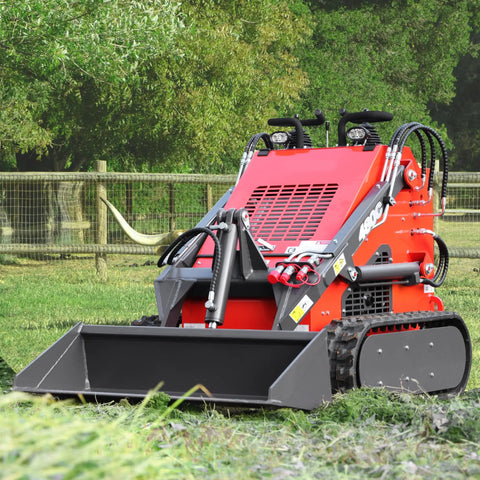 Compact Stand On Crawler Mini Skid Steer Loader With Trencher And 23 HP Gas Engine And Bucket Attachment in a grassy area