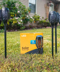 Outdoor Solar Flickering Torch Lights 8 Pack Waterproof Patio Tiki Lamps With 12 LED Flame Beams arranged in a garden