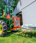 Six In One Tractor Attachment with Pallet Forks lifting 2000 lb load, visible hay spear sleeve, and headache rack on grass