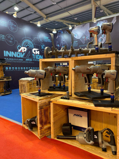 Trade show booth displaying Stubby 1/2 Inch Air Impact Wrench With Jumbo Hammer Grip, Beast Torque 550-650 Ft-Lb on wooden shelves.