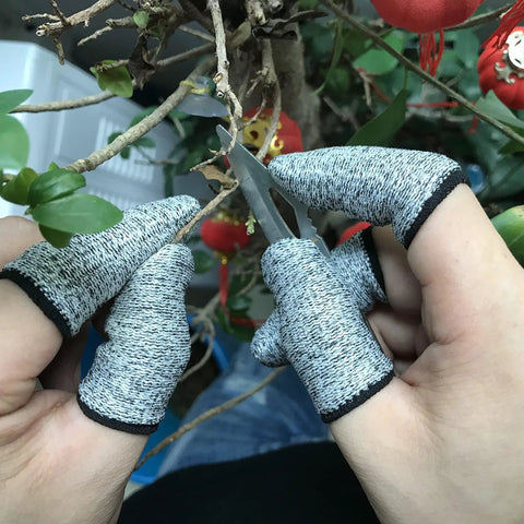 Hands wearing cut resistant finger cots using scissors for gardening, focus keyword: Cut Resistant Finger Cots 12 Pack Protective Finger Sleeves Reusable Finger Guards Anti Slip Finger Covers For Kitchen Work Arts And Crafts Sculpture Durable Breathable Fabric For Everyday Use.