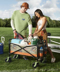 Two people using a Heavy-Duty Collapsible Beach Wagon with All Terrain Wheels and Large Storage on a grassy field.