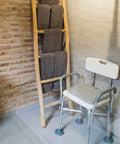 Heavy Duty Shower Chair With Arms And Back For Inside Showers, featuring non slip feet and waterproof seat next to a towel rack.