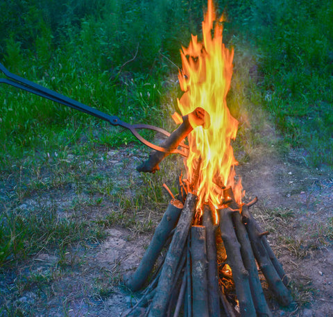 40 Inch Heavy Duty Fire Tongs With Scissor Style Serrated Claws, Long Reach Log Grabber For Fire Pit And Fireplace, Ergonomic Rubber Grip Handle, Indoor Outdoor Use, Safe, No Bending Heavy Logs gripping a burning log by a campfire