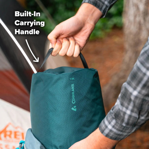 Hand holding 20L Ripstop Stuff Bag With Water Resistant DWR Coating Lightweight Outdoor Drawstring Sack beside camping tent.