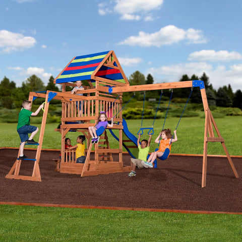 Children playing on Beachfront Cedar Wood Swing Set With Wave Slide Elevated Deck Canopy Monkey Bars Rock Wall Ladder Shaded Picnic Area Snack Bar Window Belt Swings Trapeze Sandbox Playset For Kids in backyard.