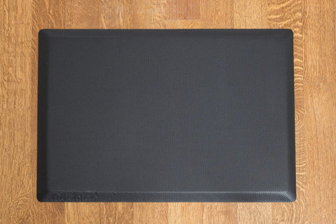 Black anti-fatigue mat included with 46 Inch Height Adjustable Standing Desk Converter, shown on wooden floor.