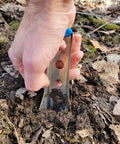 Hand using Ultralight Backpacking Trowel 0.48 Oz 13.5 G Blue With Lifetime Warranty Made In USA to dig in forest soil