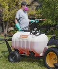 Man using Tow Behind Sprayer With 60 Gallon Capacity, 4 GPM Diaphragm Pump, 100 PSI, attached to tractor for lawn care