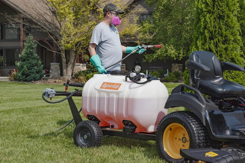 Man using Tow Behind Sprayer With 60 Gallon Capacity, 4 GPM Diaphragm Pump, 100 PSI, attached to tractor for lawn care