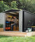 Person working inside 8 By 12 Ft Outdoor Metal Storage Shed With Updated Frame Structure, Weatherproof Tool Shed For Backyard Garden Patio Lawn, Easy Assembly, Heavy Duty Construction, UV Resistant Powder Coat, Black.