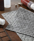 Heavy Duty Oil Absorbent Pads For Garage And Home Use, dimpled gray pads on table, absorbent and protective for spills, 9.8 x 13 inches
