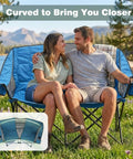 Couple sitting on Foldable Double Camping Chair With Storage for two against scenic outdoor backdrop.