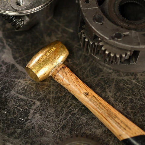Non Sparking Brass Hammer 18 Inch 5 Pound USA Made With Wood Handle And Double Faced Head resting on industrial surface