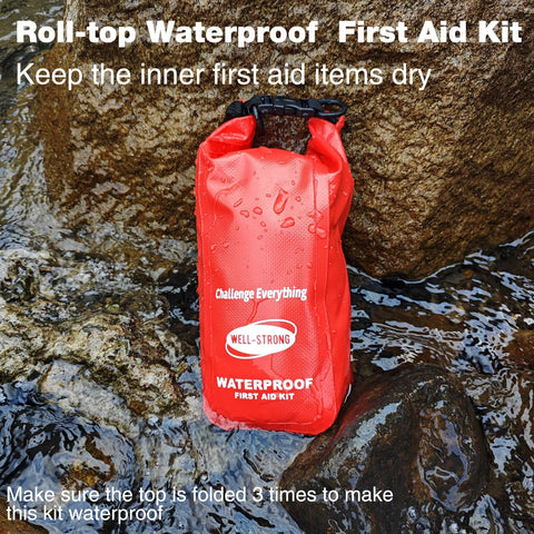 Red Well-Strong waterproof first aid kit roll-top on rocky shore, front view.