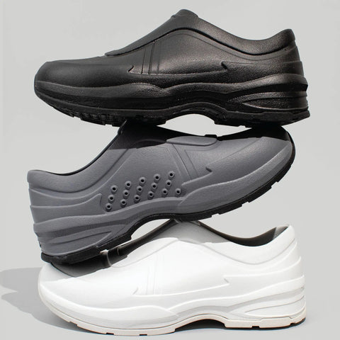 Stack of black, gray, and white slip resistant comfort work shoes for nurses and chefs with breathable ventilation.