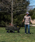 Man using Heavy-Duty Steel Utility Cart With 4 Cu Ft Bed And 900 LB Load Capacity, Black Towable Hauling Wagon With Removable Side Panels For Yard on grass.