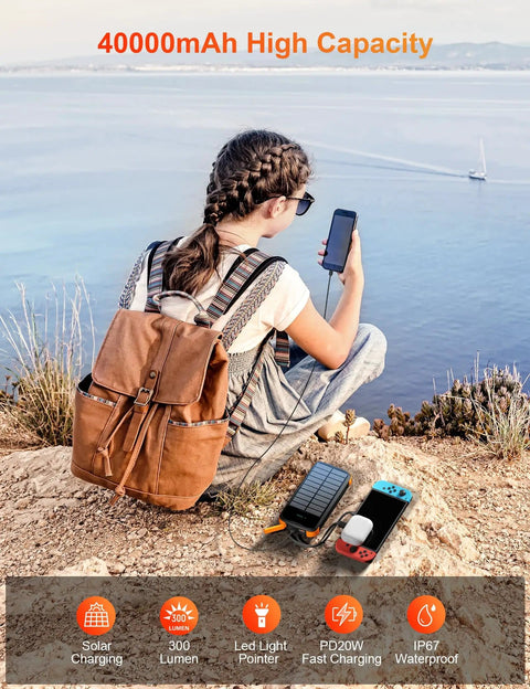 Solar Charger Power Bank 40000mAh With PD 20W Fast Charging Built In 4 Cables Dual Bright Flashlights IP67 Waterproof Outdoor Phone Charger For Camping Hiking And All Day Adventures next to person overlooking ocean